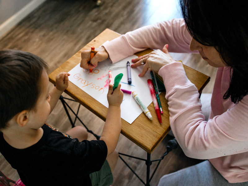 staff and volunteers - teacher helping child draw